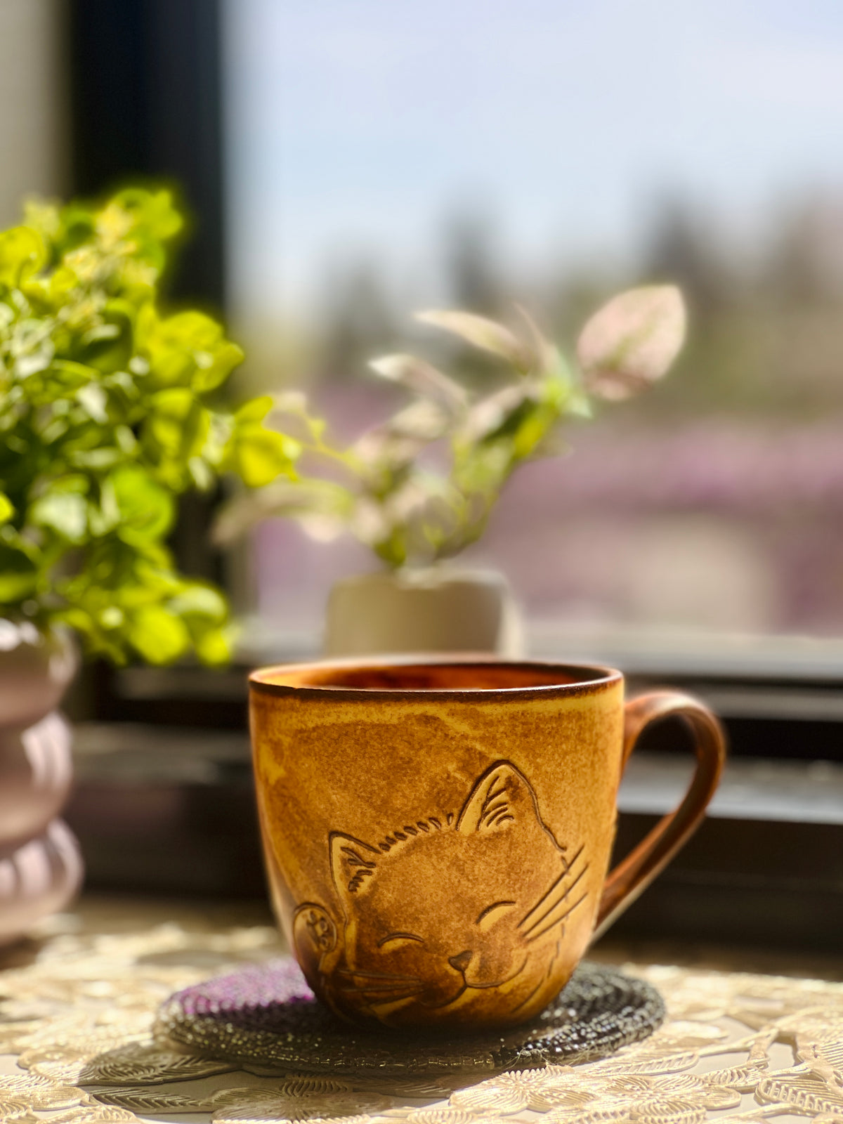 Brown ceramic mug with cat design on a table outdoors