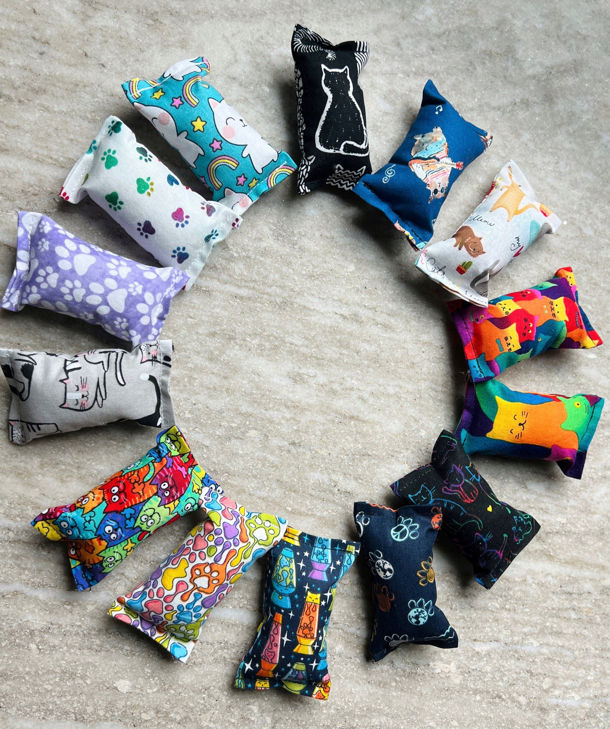 Colorful catnip toys arranged in a circular pattern on a textured surface.