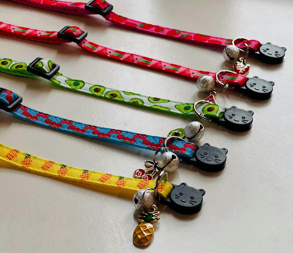 Four colorful cat collars with decorative elements on a light background