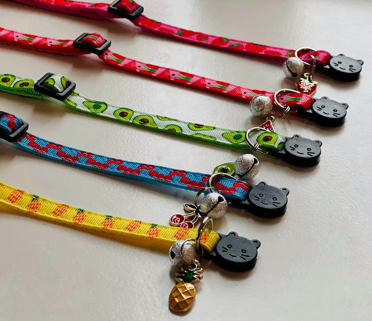 Four colorful cat collars with decorative elements on a light background