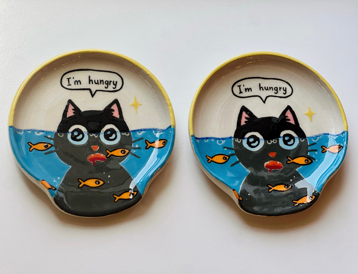 Two ceramic plates with a black cat illustration and 'I'm hungry' text on a white background.