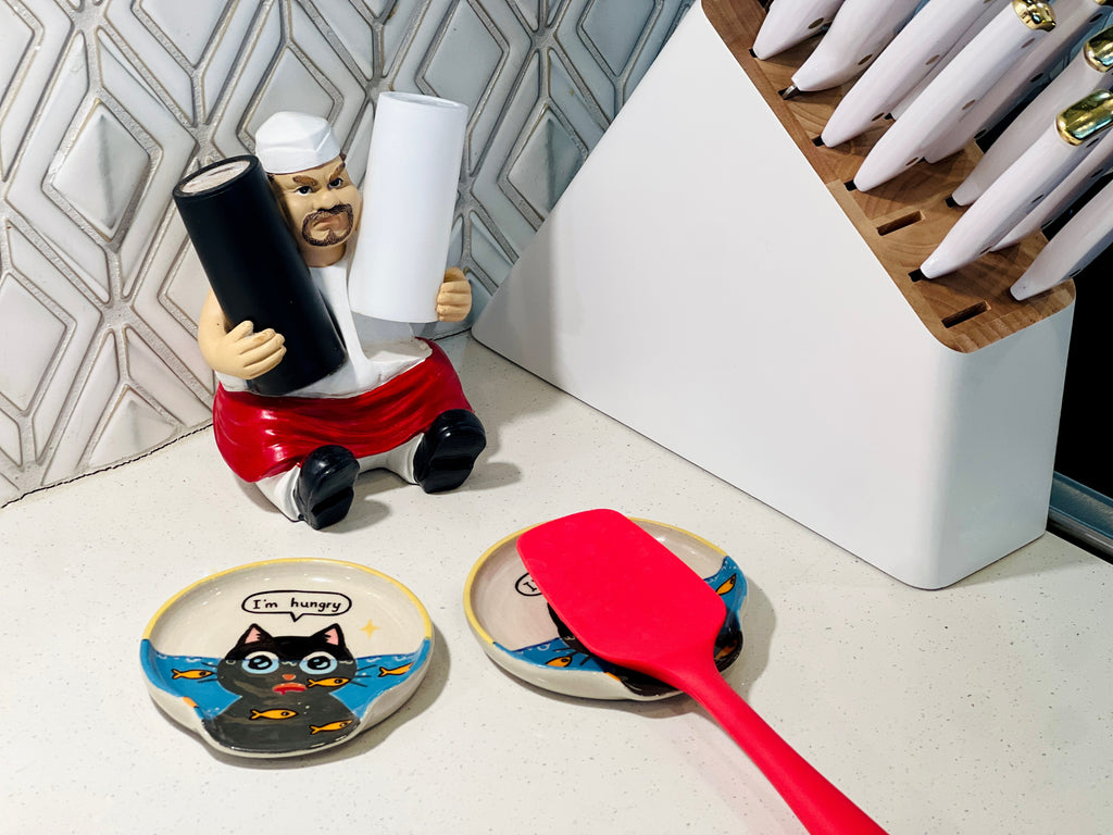 Spoon rests with a red spatula on a kitchen counter.