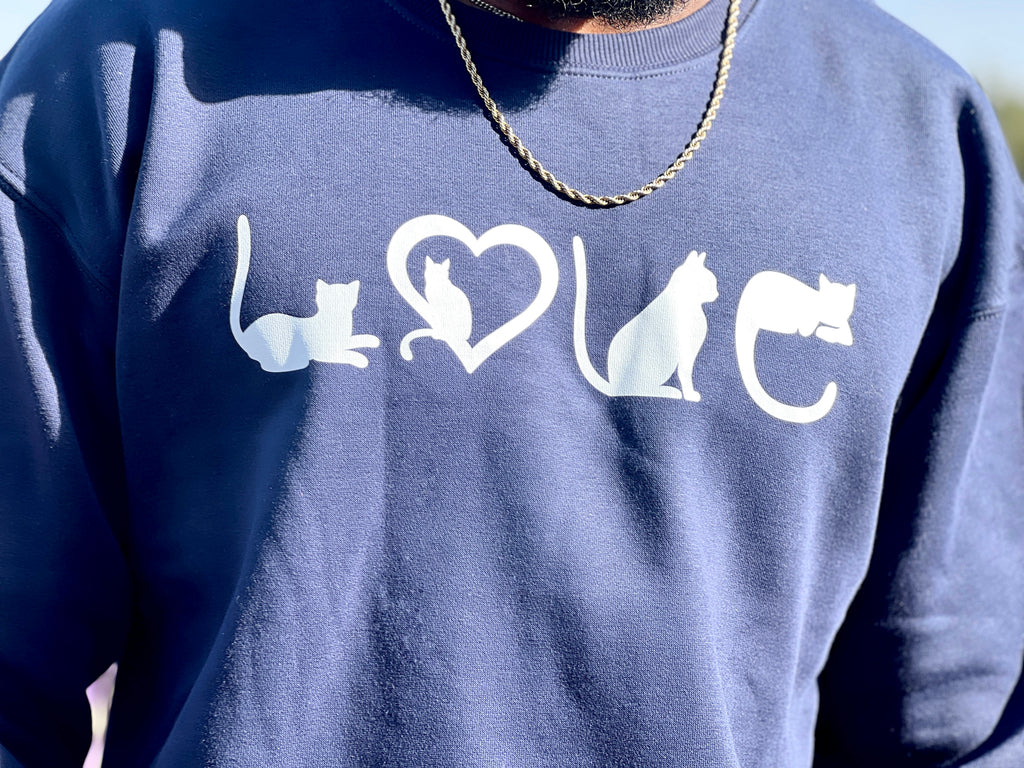 Person wearing a blue sweatshirt with white cat and heart designs.