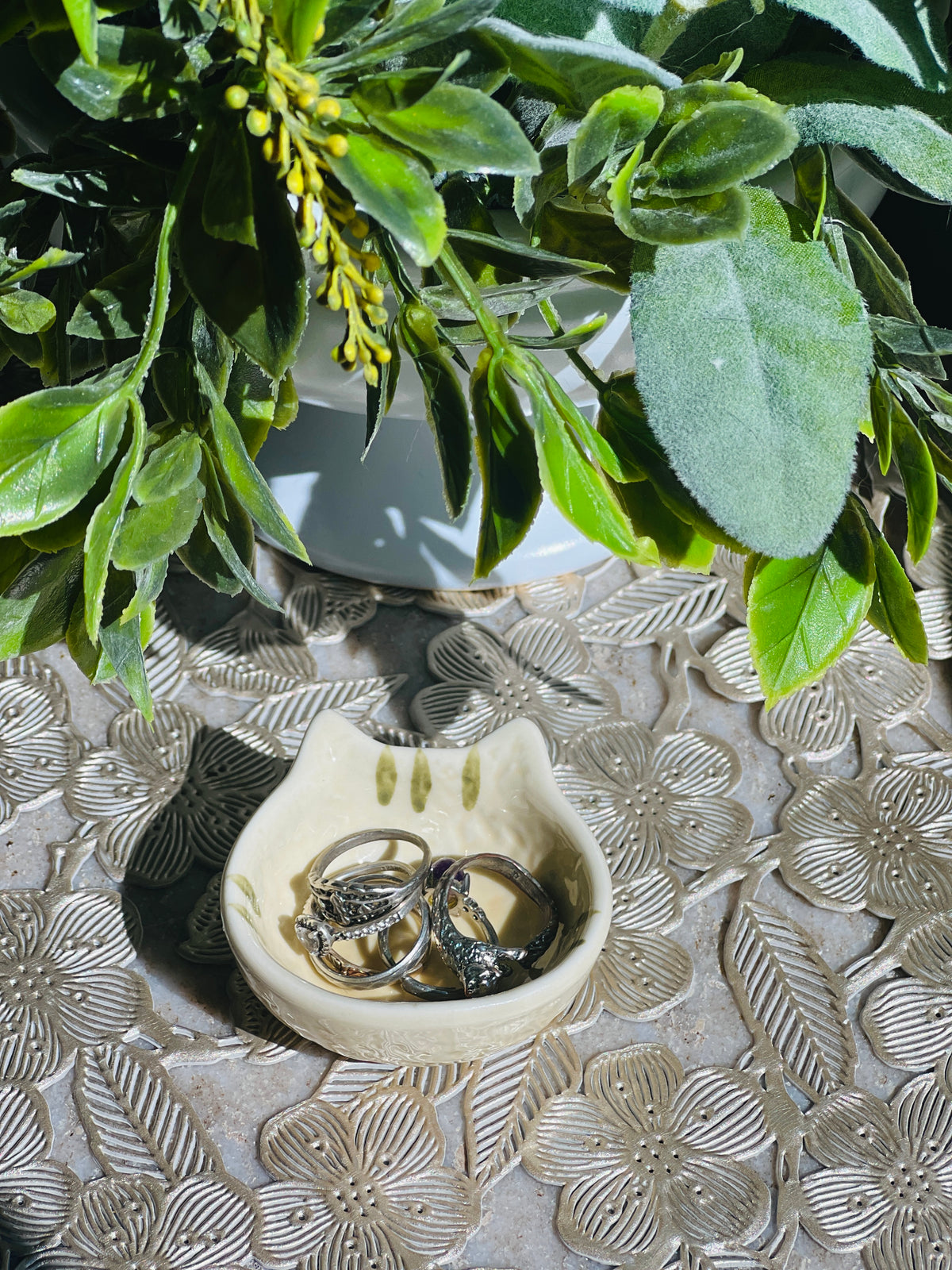 Two rings in a decorative dish with green leaves in the background