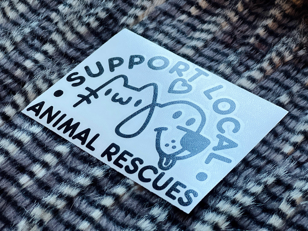 Sticker with 'Support Local Animal Rescues' text and animal illustrations on a textured surface