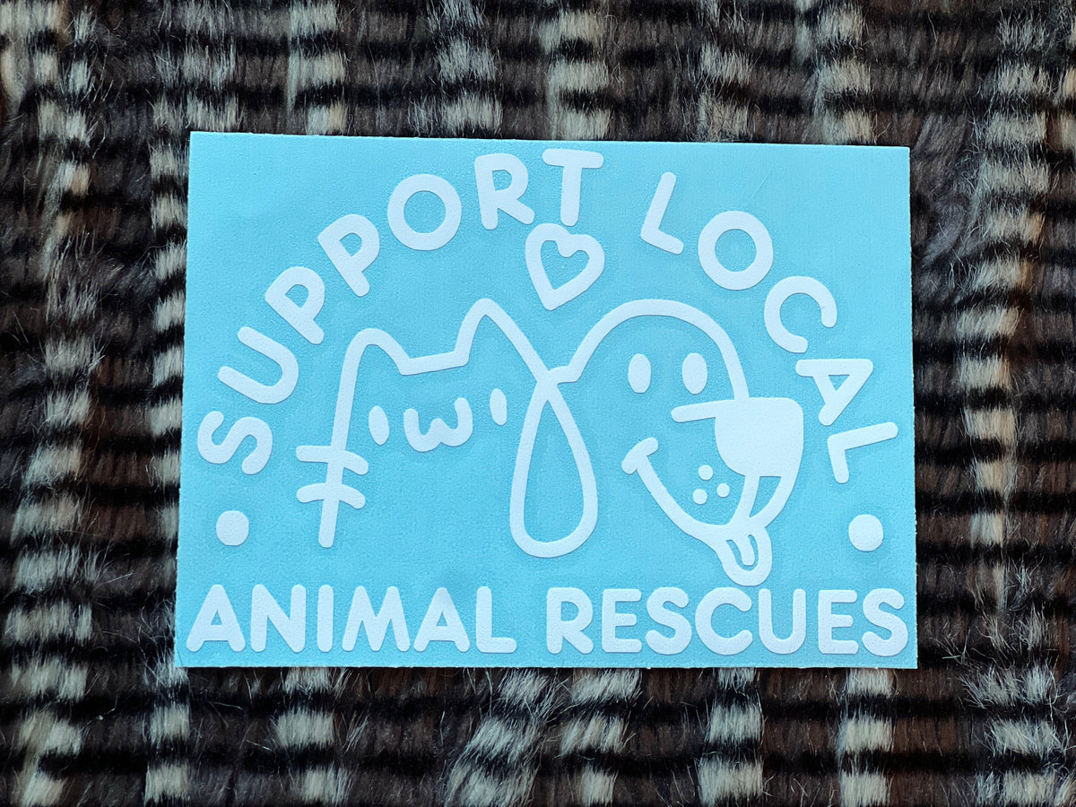 White sticker with text 'Support Local Animal Rescues' featuring a dog and cat illustration on a textured fabric background.