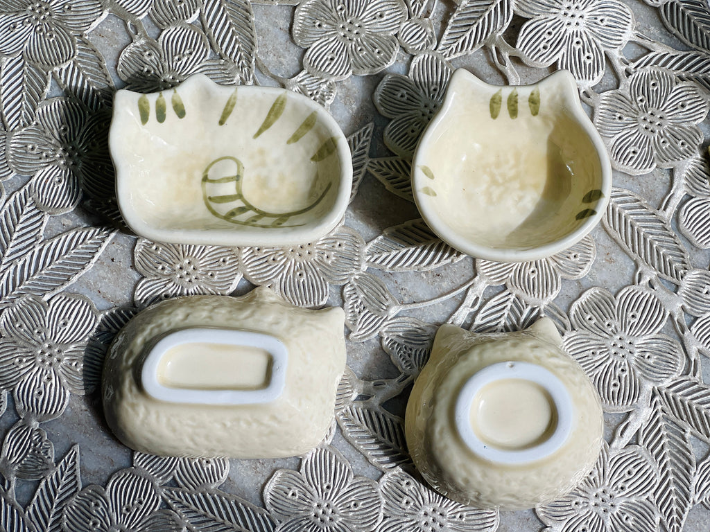 Four ceramic bowls with embossed designs on a textured surface