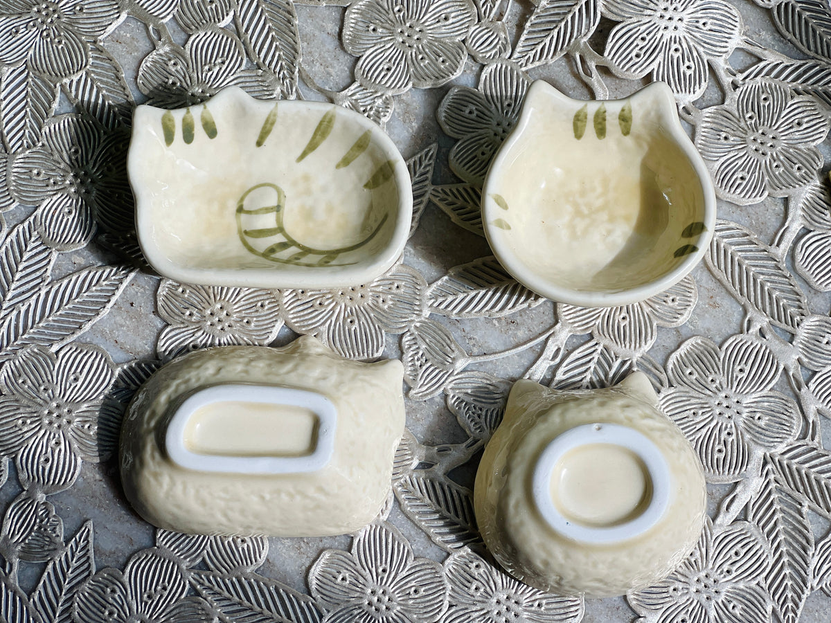 Four ceramic bowls with embossed designs on a textured surface