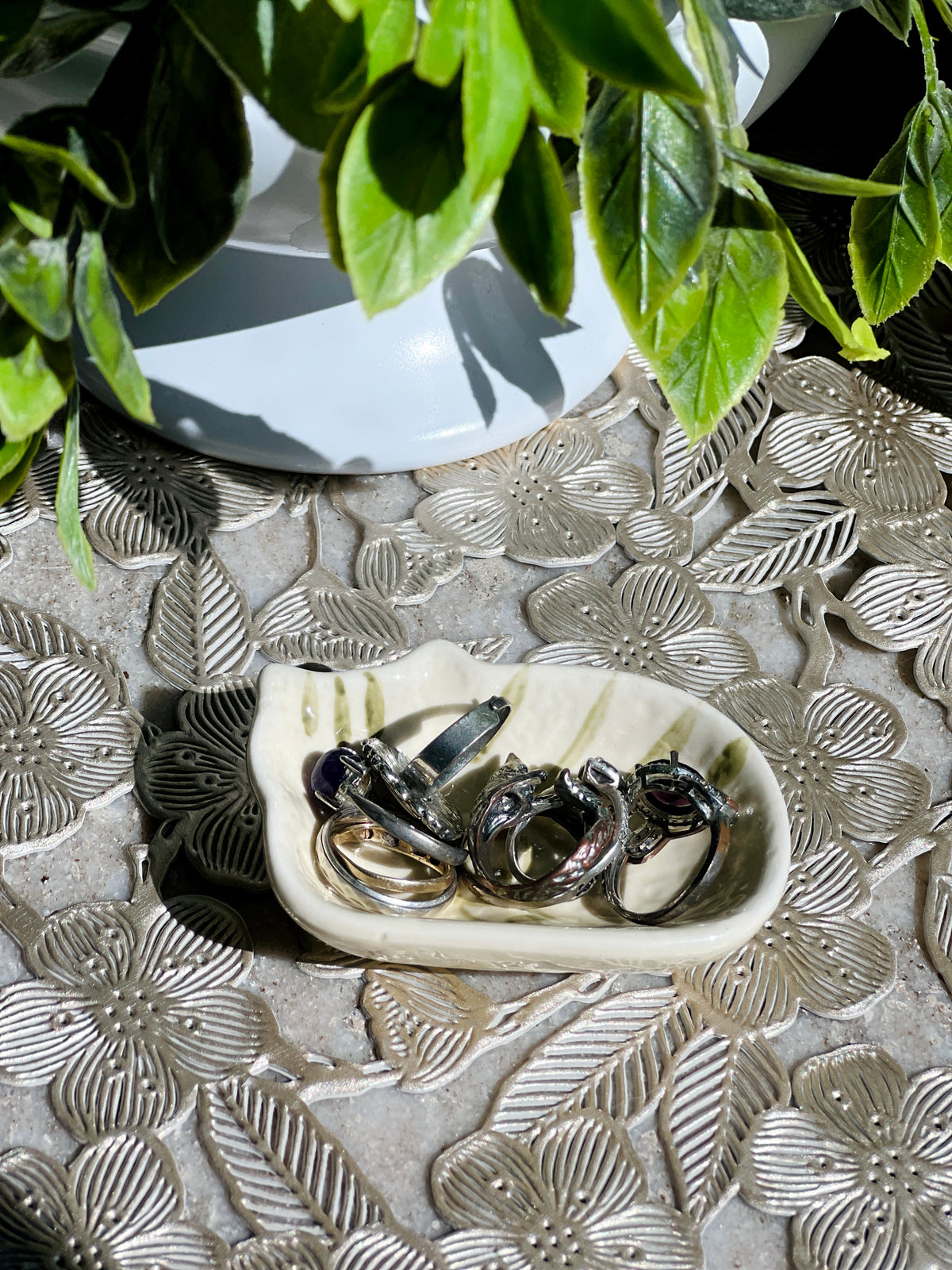 Silver rings on a decorative stone surface with green leaves in the background